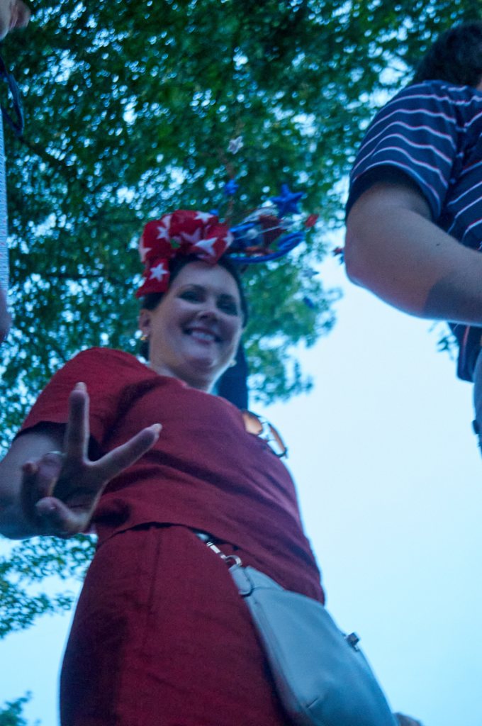 Attendee in a patriotic headpiece reaching toward the camera