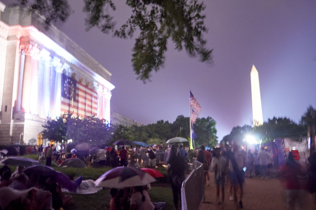 Umbrellas on the Mall with the Washington Monument under a purple sky