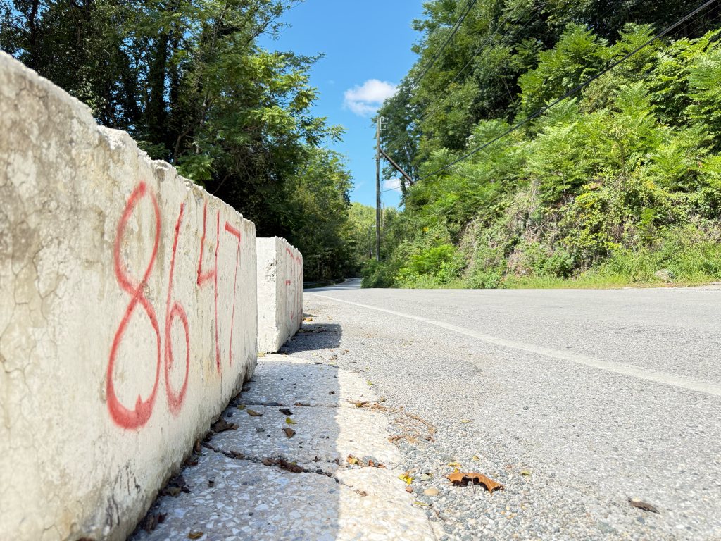 Low-angle view of a barrier painted 8647 at the road edge