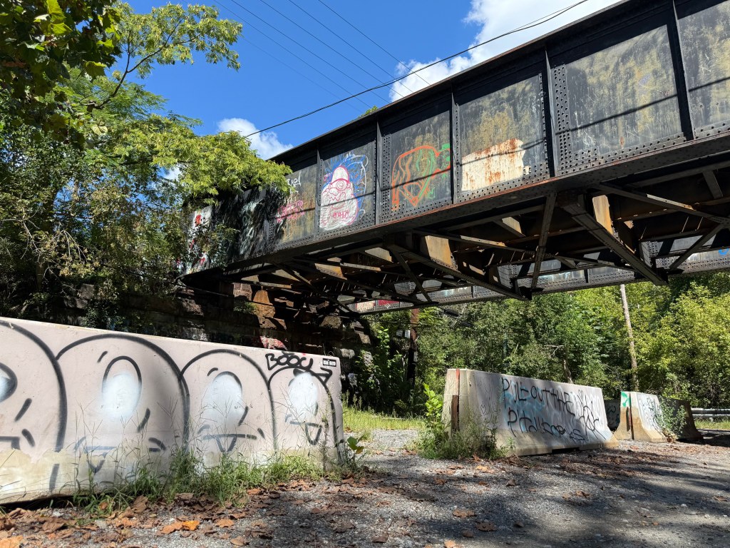 Railroad bridge over Ilchester Road with graffiti-covered barriers below