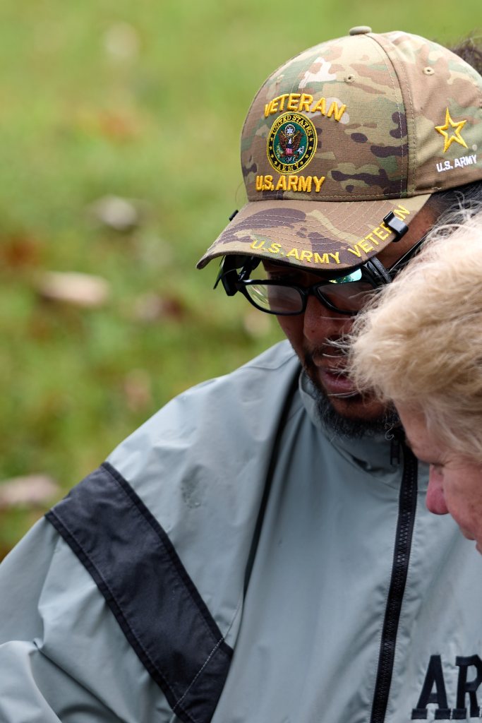 Festivalgoer in a U.S. Army veteran cap talking with another festivalgoer