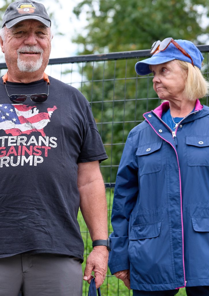 Festivalgoer in a Veterans Against Trump shirt beside a woman in a blue jacket