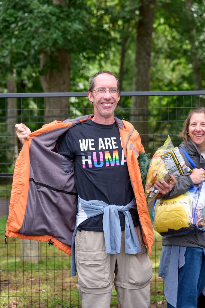 Festivalgoer opening his jacket to show a shirt reading We Are Human