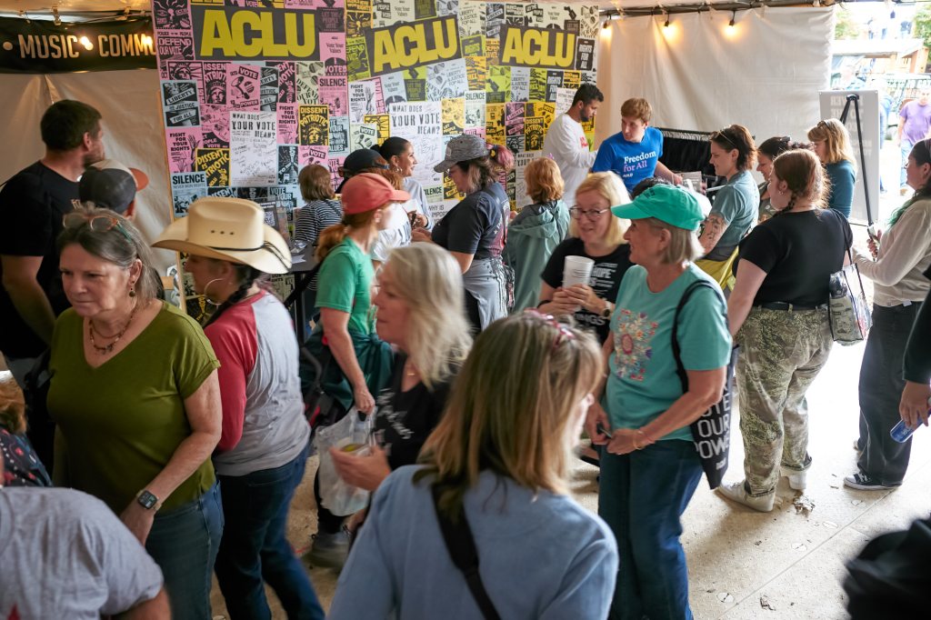 Festivalgoers filling a tent with ACLU posters on its back wall
