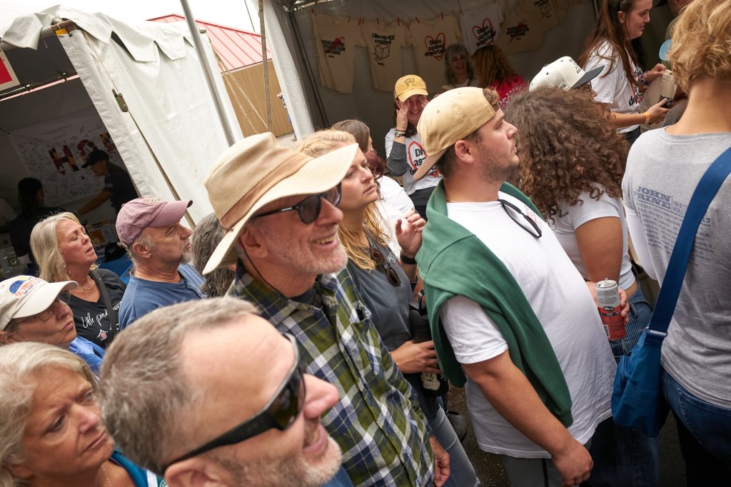 Festivalgoers in front of a tent with shirts hanging on a line