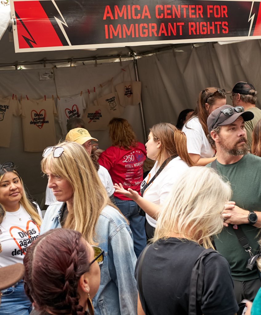 Festivalgoers outside a tent under an Amica Center for Immigrant Rights banner