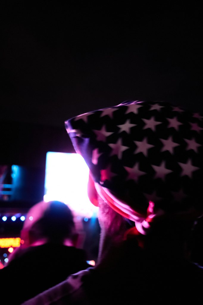 Festivalgoer in a star-print bandanna lit by stage light at night